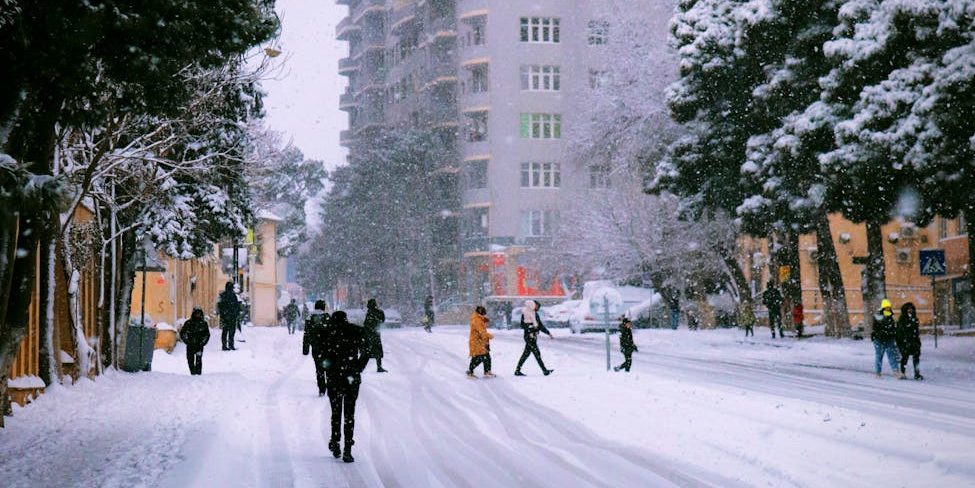 view of pedestrians walking on a snowy street in city